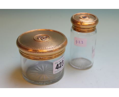 TWO 9CT.GOLD MOUNTED GLASS VANITY JARS WITH ENGINE TURNED DECORATIONS AND BEARING THE LETTER E.   £250-350