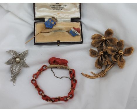 A Coral and yellow metal bracelet, the clasp carved as a recumbent lion, with shaped oval links together with costume jewelle