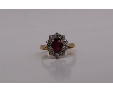 A ruby and diamond cluster ring, the central oval ruby, approximately 6mm x 5mm surrounded by ten round old cut diamonds to a