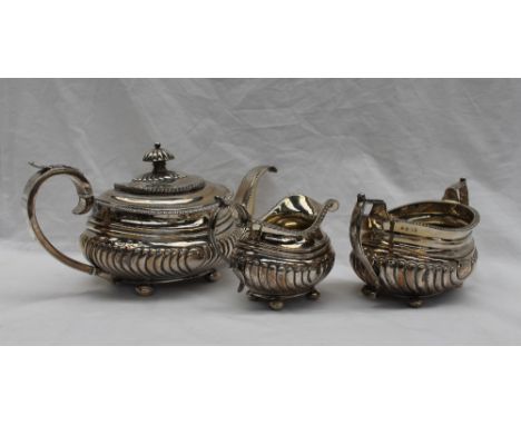 A George III silver three piece teaset, comprising a teapot, twin handled sugar basin and cream jug, with a gadrooned rim and