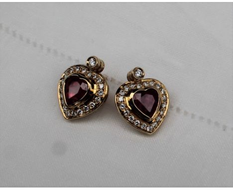 A pair of heart shaped ruby and diamond stud earrings, the central heart shaped ruby, measuring approximately 7mm x 6mm, surr