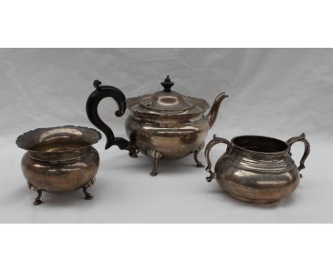 A George V silver teapot with a flared rim, circular body on four leaf capped legs with pad feet together with a matching sug
