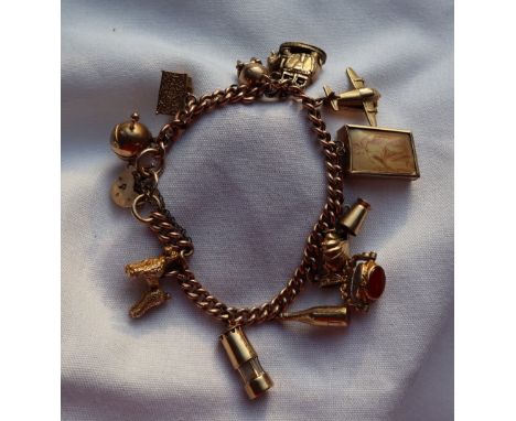 A 9ct yellow gold charm bracelet, set with numerous charms including a shell, tankard, 10 shilling note, revolving fob, bottl