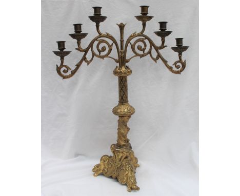 A gilt metal six branch candleabra, with a leaf capped scrolling support, the column cast with a trellis pattern, the tripod 