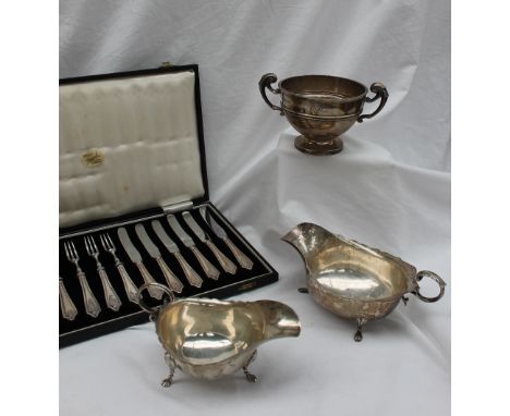 A George V silver sauce boat, with a flared rim, leaf scrolling handle on three paw feet, Chester, 1912, together with anothe
