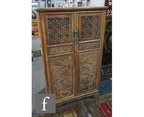 A South East Asian carved hardwood double door food cabinet, with pierced trellis work upper panels, the lower door carved in