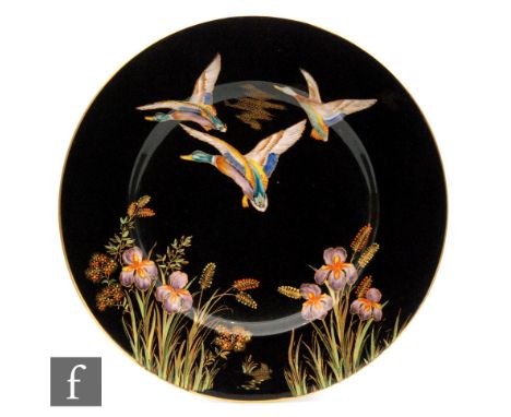 A 1930s Carlton Ware plate decorated in the Mallard Duck pattern with two gilt and enamel birds in flight against a black gro