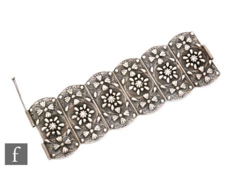 A Chinese low grade silver filigree work cuff bracelet, the six panel bracelet adorned with lotus flower heads before a scrol