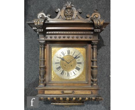 A late 19th Century walnut wall mounted wall clock, the brass dial and silvered chapter ring with eight day movement below a 