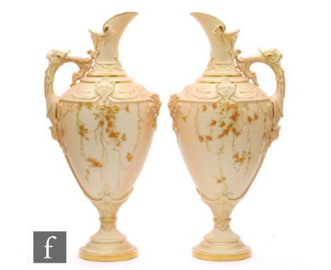 A pair of late 19th Century Royal Worcester blush ivory pedestal jugs, shape 1742, each decorated with a spray of gilt flower