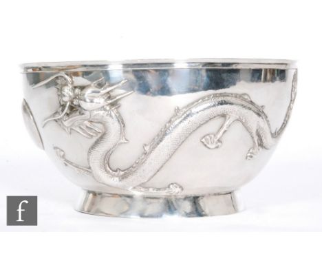 An early 20th Century Chinese silver bowl, the U shaped bowl, rising from a high footring, the two four-clawed dragons in pur