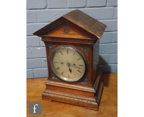 A late 19th Century oak cased bracket clock of architectural form, carved in the Aesthetic taste with a twin fusee 8 day move
