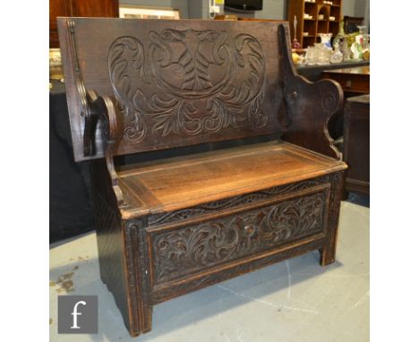 A Victorian carved oak monks bench, the fold over top over a panelled carved front, height 82cm x depth 54cm x width 109cm. 