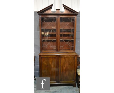 A George IV mahogany bookcase cabinet, with an architectural cornice above astragal glazed double doors and a double door cup