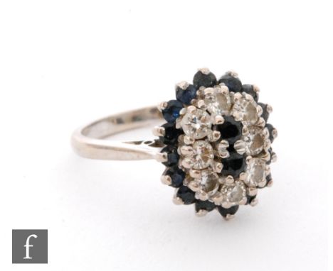 An 18ct hallmarked white gold sapphire and diamond cluster ring, two central sapphires within a border of diamond and further