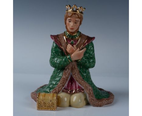 Gaspar, one of the three wise men, kneels beside a small treasure chest, dressed in a vibrant green, yellow, and pink ensembl
