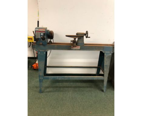 AN AXMINSTER WOOD TURNING LATHE ON STAND WITH INSTRUCTION MANUAL.