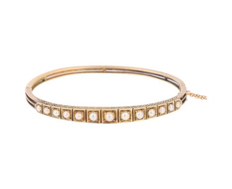 An Antique Victorian 18ct gold pearl hinged bangle, circa 1900, set with a graduated row of pearls with chased decoration, un