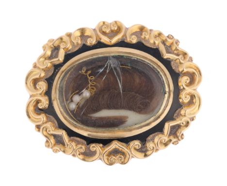 An Antique Victorian hairwork enamel mourning brooch, circa 1880, the central oval glazed compartment containing hairwork wit