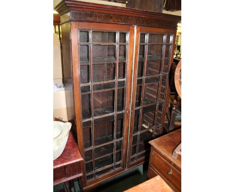 Edwardian mahogany bookcase, the down-swept pediment above two astragal glazed doors opening to reveal four interior shelves,