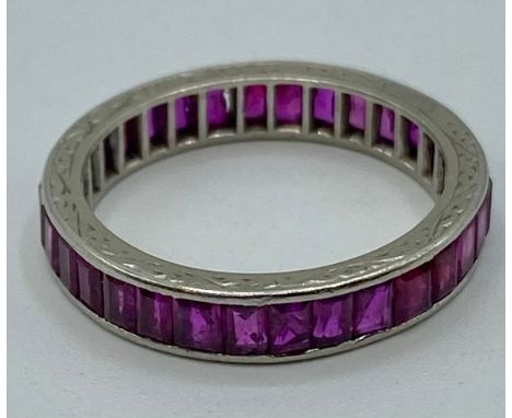 A platinum and ruby set full eternity ring. 32 channel set baguette cut rubies. Size M. 3.6g. (condition report - some minor 