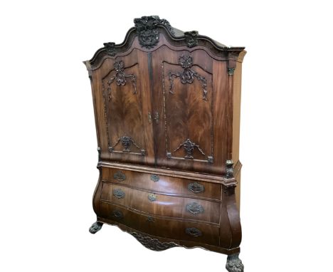 A large Dutch flame mahogany bombe commode / linen press, with carved decoration on large paw feet,  with carved crest finial