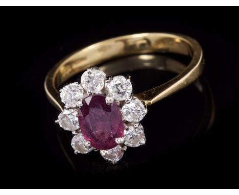 Ruby and diamond cluster ring with an oval mixed cut ruby, measuring approximately 7.25mm x 5.2mm x 2.08mm deep, surrounded b