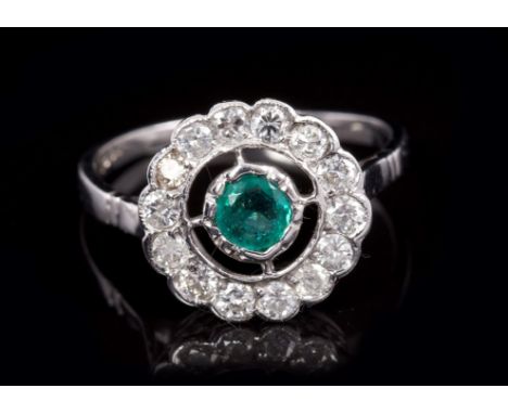 Emerald and diamond cluster ring with central round mixed cut emerald in an openwork design, surrounded by fourteen brilliant