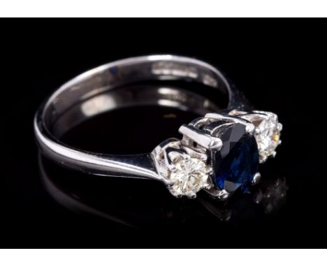 Sapphire and diamond three stone ring with an oval mixed cut blue sapphire flanked by two brilliant cut diamonds estimated to