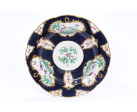 18th century Worcester plate with polychrome painted exotic bird and insect reserves within gilt borders and blue scale groun