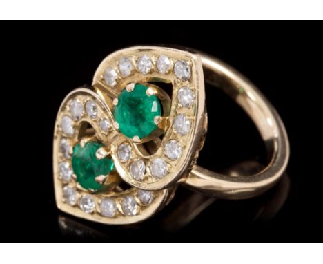 Emerald and diamond cocktail ring in the form of two interlocking hearts, set with two mixed cut emeralds surrounded by an in