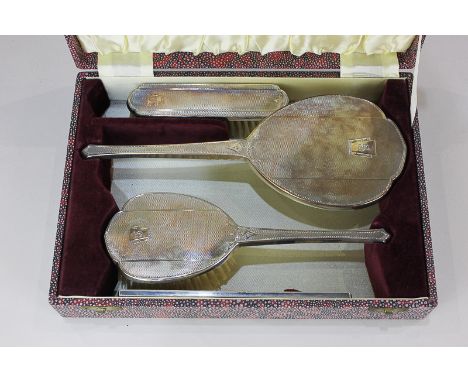 A George VI silver four-piece cased dressing table set, of two brushes, hand mirror and comb (some damage), with engine turne