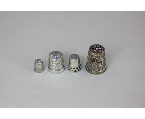 A sterling silver thimble and three other size thimbles including one with a floral enamel top
