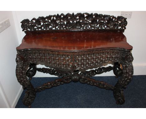 An Anglo Indian carved hardwood side / console table with serpentine top and raised foliate pierced back, with cabriole legs 