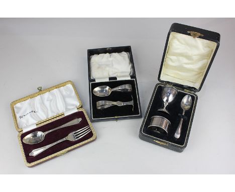 A George V cased silver christening set of egg cup, napkin ring and teaspoon, Birmingham 1931, another cased set of spoon and