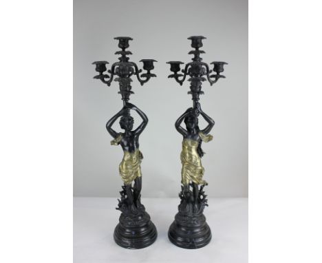 A pair of spelter figural candelabra depicting a man and a woman in flowing brass robes, each supporting a four branch candle