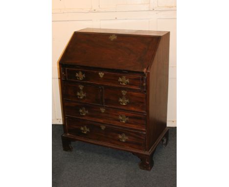 A George III mahogany bureau with fall-front (a/f) enclosing well, small drawers and pigeon holes, over two short and two lon