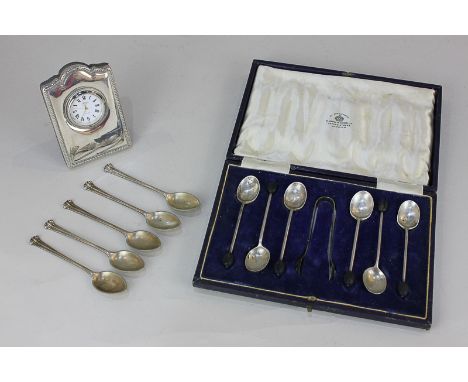 A modern silver mounted dressing table clock with engraved initials, a cased set of George V silver coffee spoons and sugar t