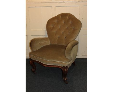 A green upholstered button back armchair with padded arms and seat, on cabriole legs, scroll feet and castors