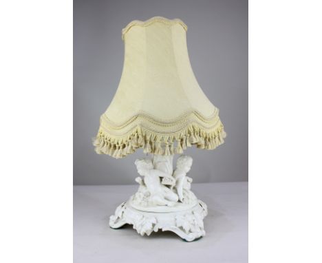 A porcelain table lamp, in the form of three putti seated amongst grapes and wheat, on scrolled base decorated with grapes an