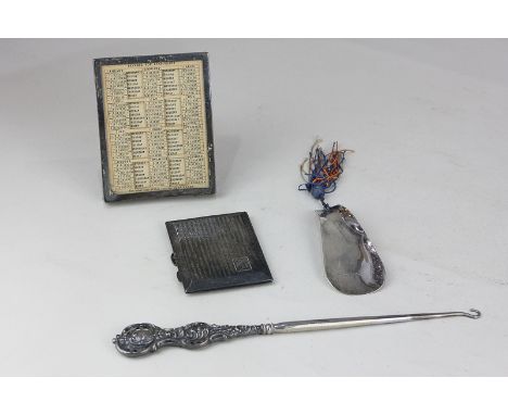 A George V silver framed desk calendar, 11cm, a cigarette case, shoe horn and silver scroll handled button hook