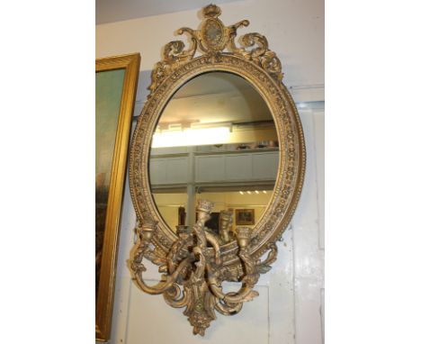 A giltwood and gesso oval girondelle wall mirror with shield and foliate pierced surmount, and three light candle holders, 11