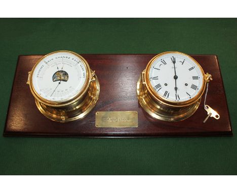 A brass porthole clock and barometer by Hermle, the clock with ships bell chime, mounted on a wooden board with plaque 'Engin