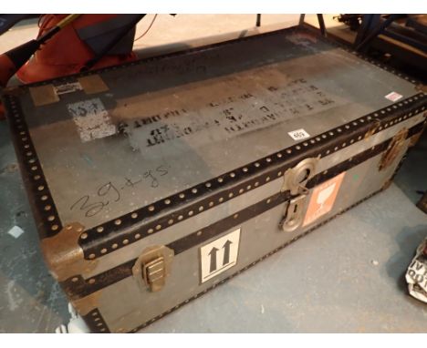 Large metal travel trunk with riveted metal banding and the labels to the exterior