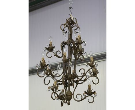 A late 20th century tole painted wrought metal twelve-light chandelier with scrolling branches and leaf mounts, hung with gla