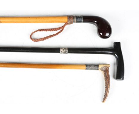 An early 20th century walking cane with a silver collar and amber-coloured resin handle, length 80cm, an ebonized walking sti