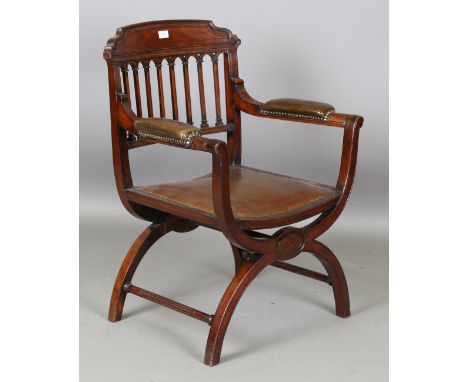 A 20th century mahogany comb back elbow chair with an 'X' framed base and upholstered in brown leather, height 86cm, width 65