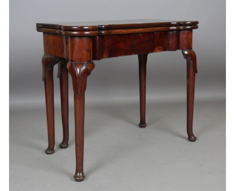A George I red walnut fold-over card table, the hinged top with projecting rounded corners, the tapering legs with carved lap