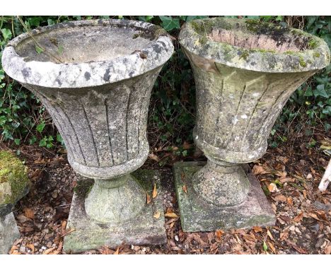 A pair of cast reconstituted stone garden planters of tulip form on circular bases, each 42cm diameter x 65cm highCondition r