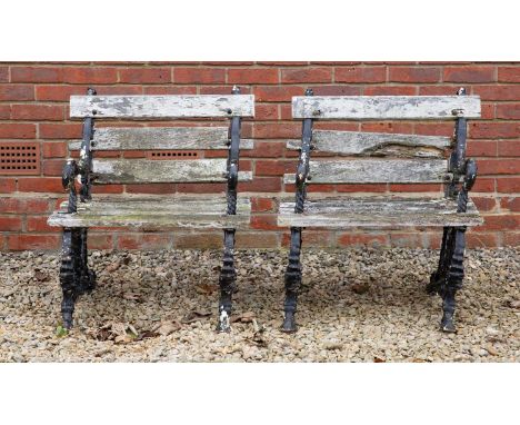 A pair of cast iron framed garden chairs, the white painted slat backs and seats with arms and supports of scrolling fruiting